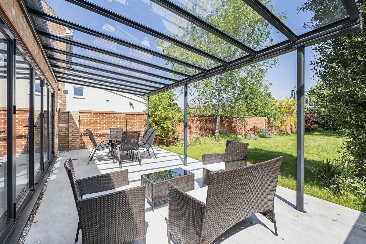 Garden patio with glass pergola, rattan seating and dining set