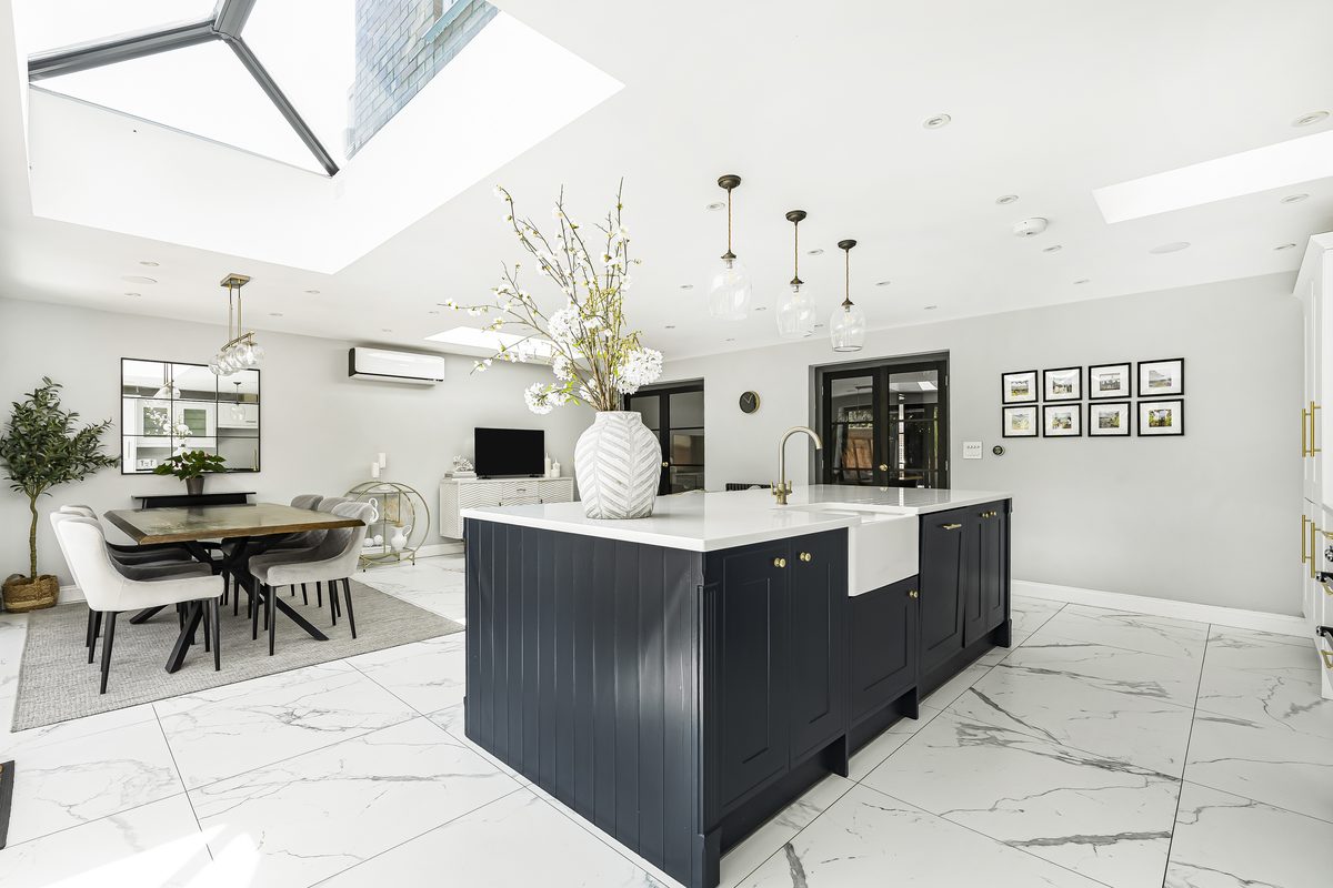 A premium serviced kitchen — marble flooring, navy shaker island and pendant lighting